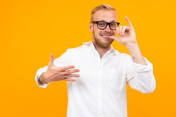 Beautiful caucasian man with glasses gesticulates isolated on yellow background