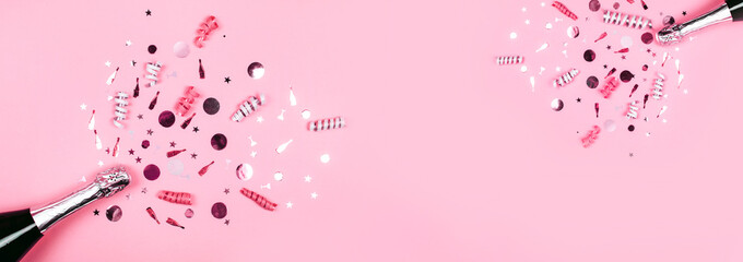 Bottle of champagne with splash of confetti. Flat lay style.