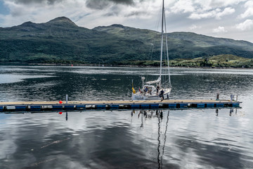 The boat stands on the dock in front of the mountains in highlands, Scotland
