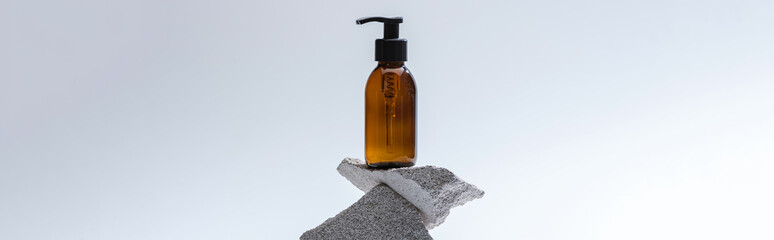 dispenser cosmetic bottle on stones on white background with back light, panoramic shot