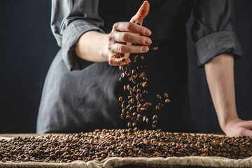Hand pouring fragrant coffee beans on a pile of roasted Arabica grains. Selection of fresh coffee...
