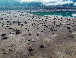 Dramatic aerial Photography of Rattlesnake lake surrounded by tree trumps and clouds reflecting off the shallow lake in the fall with the fog covered mountains in near distance in Washington State