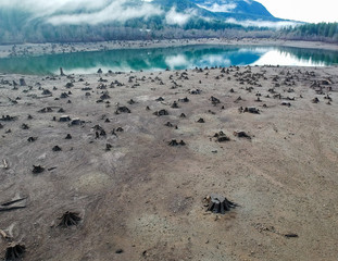 Dramatic aerial Photography of Rattlesnake lake surrounded by tree trumps and clouds reflecting off the shallow lake in the fall with the fog covered mountains in near distance in Washington State