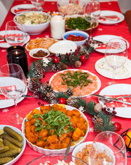 Served table with christmas decoration, red napkin, garland and candles. 