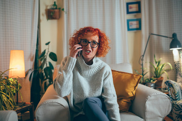 woman sitting sofa at home talking on mobile phone