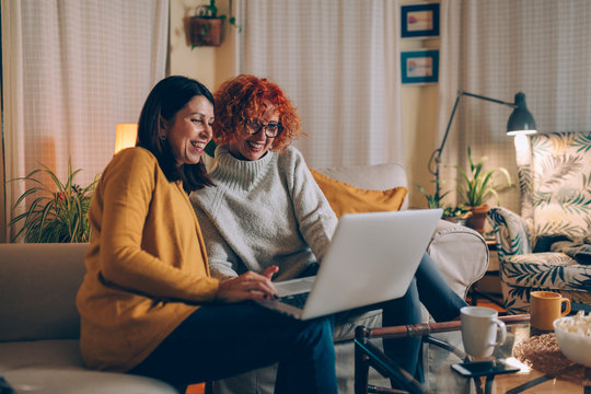 middle aged female friends having fun at home, using laptop computer
