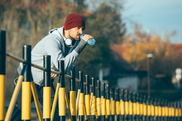 handsome young man jogging outdoor, drinking water