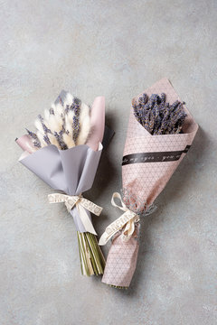 Two bouquets of lavender and lagurus in the package on a light concrete background.