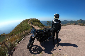 Obraz premium Biker woman journey by motorcyclewith peak of mountains scenery background. Biker lifestyle relaxing in freedom with modern vintage design motorbike. Success in your life concept.