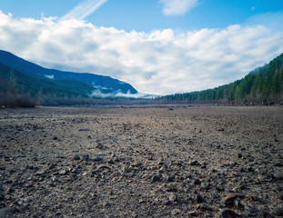Dramatic aerial Photography of Rattlesnake lake surrounded by tree trumps and clouds reflecting off the shallow lake in the fall with the fog covered mountains in near distance in Washington State