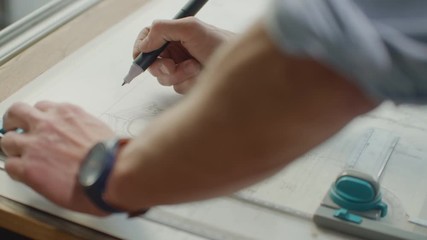 Close up of architect hands making house blueprint in the office near window. Concept: architecture, blueprint house, paper work.