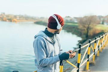 handsome young man preparing for jogging outdoor, setting up tunes on his mobile phone