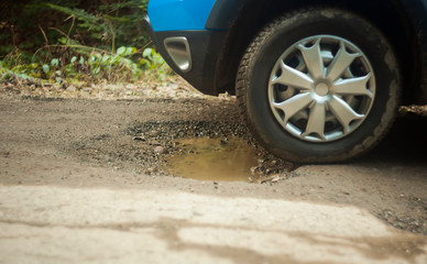 car tire in damaged road with hole in the asphalt. focus on the tire
