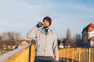 handsome young man jogging outdoor, drinking water