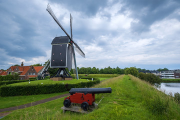 Die historische Windmühle von Brielle/Niederlande und eine alte Kanone im Vordergrund
