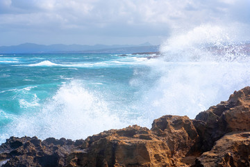 spray from the crashing waves on the rocks against the blue sky