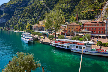 Fototapeta premium Riva del Garda,Lago di Garda ,Italy - 13 October 2019:Tourists enjoying a walk around Lake Garda, colorful autumn in Riva del Garda surrounded by mountains, Trentino Alto Adige region, Lago di garda, 