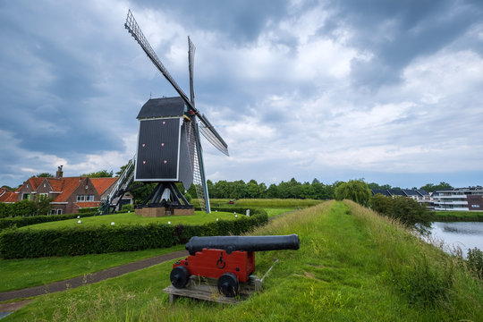 Die historische Windm&uuml;hle von Brielle/Niederlande und eine alte Kanone im Vordergrund