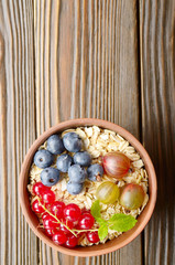Obraz na płótnie Canvas Flat lay view at oats in clay bowl with berries on wooden table