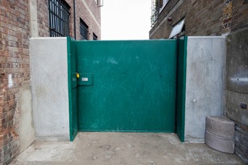 Closed green gate connected to buildings
