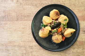 deep fried egg tofu with minced pork topping slice mushroom in sweet and sour gravy sauce on plate