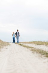 Full length of young hiking couple walking on path at field