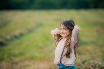 Obraz premium Close up of a child in a pink blouse with long dark hair in an open field.