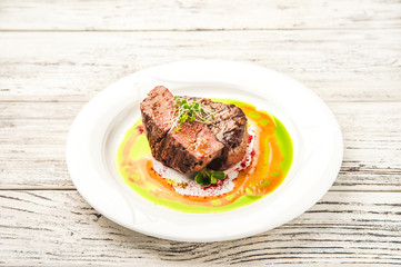 Tornedo in a restaurant close-up. Beef tenderloin steak with microgreens on a white plate and copy space.