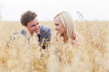 Happy man looking at woman while relaxing amidst field
