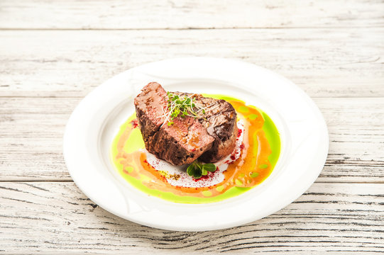 Tornedo in a restaurant close-up. Beef tenderloin steak with microgreens on a white plate and copy space.