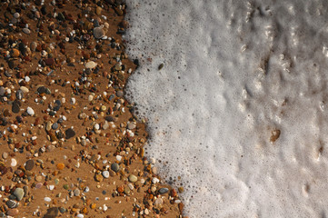 Sand, rocks and foam on the resort beach close-up