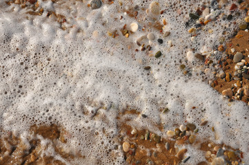 Sand, rocks and foam on the resort beach close-up