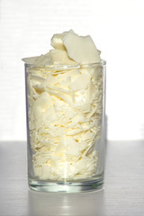 Close up of white soy wax flakes for candle making in glass. Ingredient for homemade candles. Ecological lifestyle