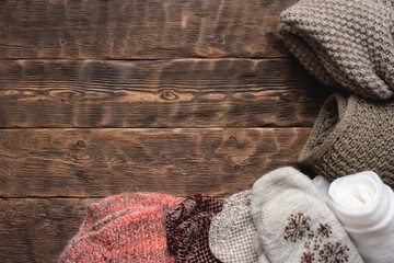 Winter warm clothes on brown wooden table background.