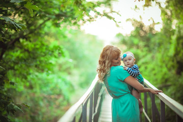 Mom walks with the child in nature and goes on a forest trail across the bridge.