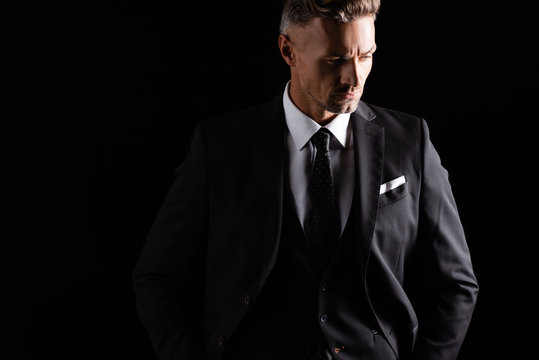 Serious handsome businessman looking away isolated on black