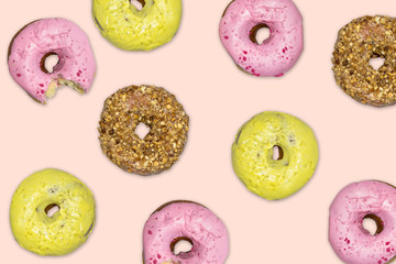 Multicolored donuts with icing on pink background. Top view, flat lay.