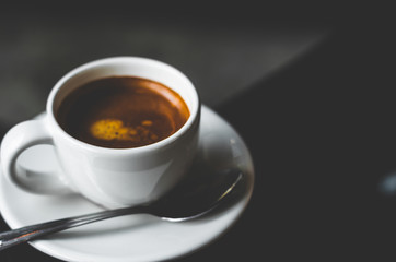 close up coffee on wood table with coffee bubble foam pattern and texture in white cup in dark background looking and feel so delicious on glasses table in coffee shop.