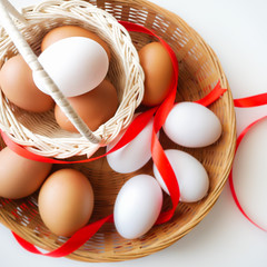 Healthy food concept, Isolated gift set of fresh duck and chicken eggs in basket with red ribbon decorated on white table background-top view
