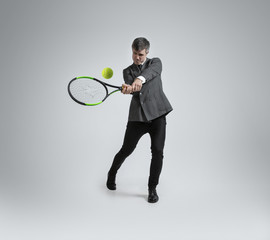 Time for movement. Man in office clothes plays tennis isolated on grey studio background. Businessman training in motion, action. Unusual look for sportsman, new activity. Sport, healthy lifestyle.