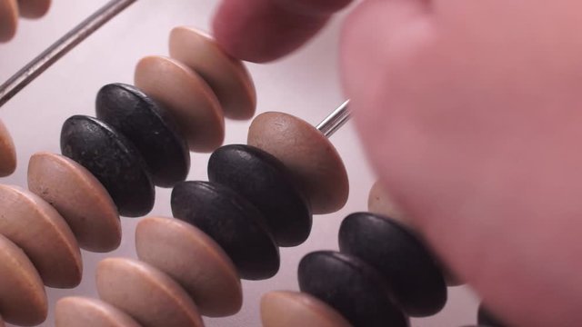 Accountant uses vintage wooden abacus on a white background. He moves wooden knuckles with his hand. Macro video