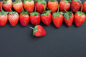 top view of a red strawberry placed on a black table with a copyspace