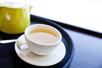 Cup of Green Tea on a tray with saucer and spoon
