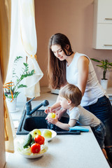 the little boy is helping mom in the kitchen