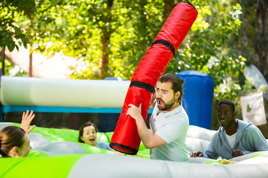 Team Of Friends Playing With Inflatable Sticks On The Trampoline