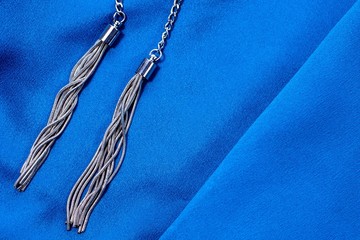 Dark blue colored fabric background with two silver pendants.