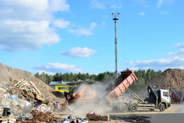 Garbage truck unloads construction waste from container at the landfill. Industrial waste treatment...