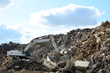 Fototapeta premium Salvaging and recycling building and construction materials. Industrial waste treatment plant. Excavator work at landfill with concrete demolition waste. Re-use concrete for new construction