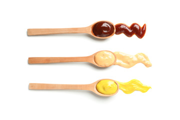 Wooden spoons with sauces isolated on white background