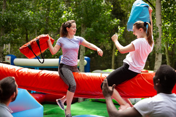 Cheerful girlfriends fighting with inflatable pillows in an amusement park